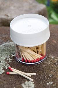 The 4oz Storage Jar with a white lid contains wooden matches, with several matches scattered on a stone surface nearby.