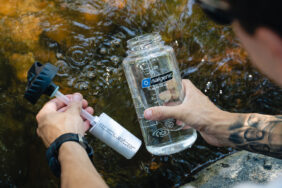 A person fills their bottle with stream water using the 32oz/24oz Epic Filter Cap + Kit.