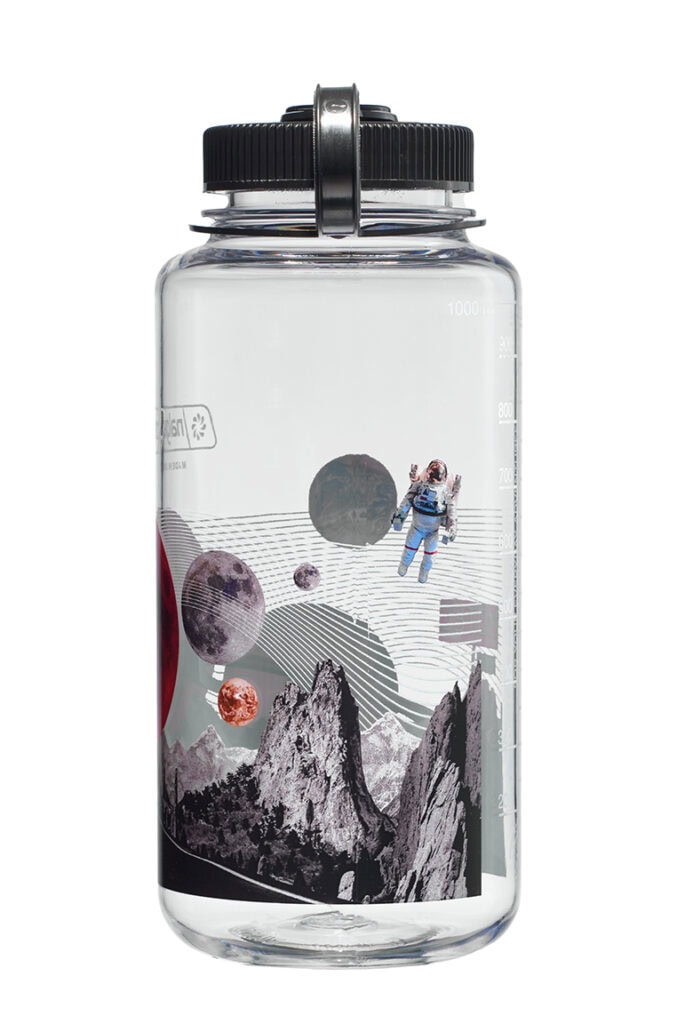 The 32oz Wide Mouth Surrealist Bottle features a clear design with planets, mountains, and an astronaut floating in space.